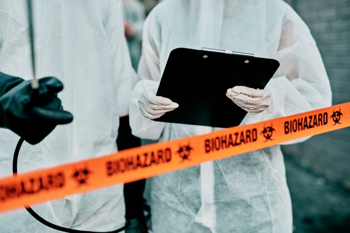 Two remediation technicians in protective suits coordinating on site